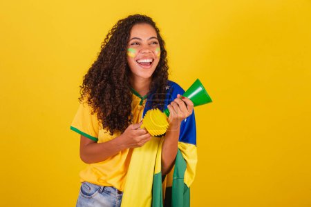 Photo for Young black Brazilian woman, soccer fan. with the horn making noise. - Royalty Free Image