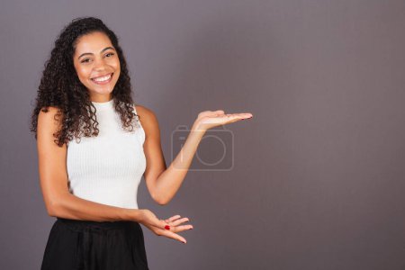 Téléchargez les photos : Jeune femme noire brésilienne présentant avec ses mains à droite, photo de publicité. - en image libre de droit