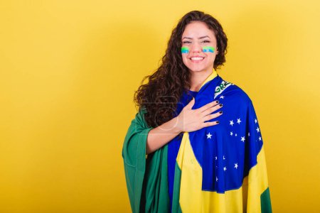 Téléchargez les photos : Fan de football féminin, fan du Brésil, Coupe du monde, chantant l'hymne national. main sur la poitrine. - en image libre de droit