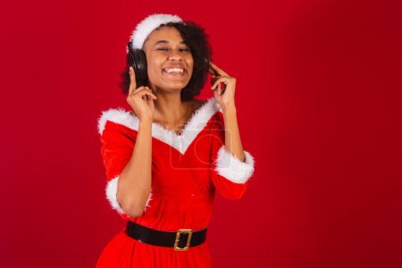 Photo for Beautiful black brazilian woman, dressed as santa claus, mama claus, dancing with headphones - Royalty Free Image