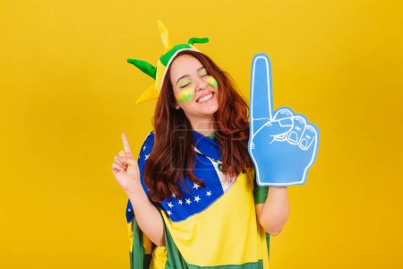 Photo for Caucasian woman, redhead, soccer fan from Brazil, using foam finger, cheering, coleographed dance. - Royalty Free Image
