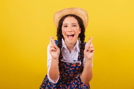 Photo for Girl wearing typical clothes for Festa Junina. Fingers crossed, twisting, wishing. For the Arraia party - Royalty Free Image