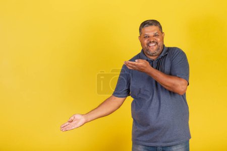 Foto de Hombre negro brasileño, adulto sonriendo, presentando algo a la izquierda, foto publicitaria - Imagen libre de derechos