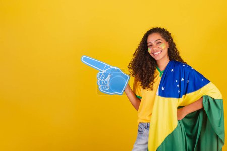 Photo for Young black Brazilian woman, soccer fan. with foam finger pointing to the left. - Royalty Free Image