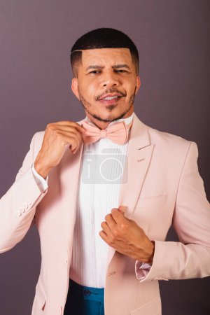 Téléchargez les photos : Brésilien homme noir, avec costume rose et noeud papillon, fond gris, cravate de fixation - en image libre de droit