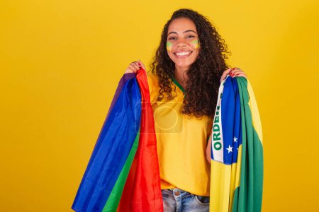 Téléchargez les photos : Jeune Brésilienne noire, fan de foot. avec le drapeau LGBT et brésilien, Lutte contre les préjugés. gravité - en image libre de droit