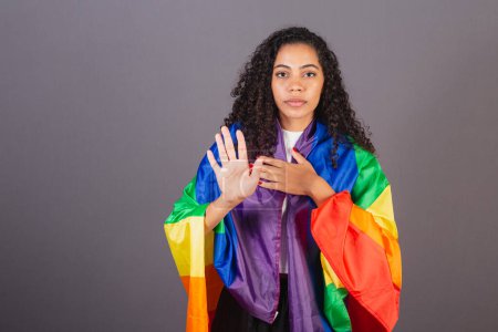Photo for Young Brazilian black woman, stop sign with hand, militancy with LGBT flag, diversity, fight against prejudice. - Royalty Free Image