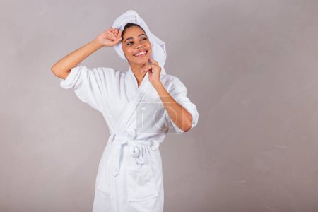 Téléchargez les photos : Belle femme noire brésilienne, portant peignoir et serviette. concept de bien être, spa, esthétique, délicatesse. - en image libre de droit