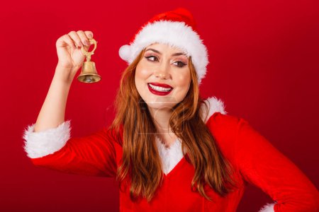 Téléchargez les photos : Belle femme rousse brésilienne, vêtue de vêtements de Noël, le Père Noël. utilisant la cloche de Noël. - en image libre de droit
