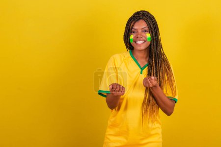 Foto de Mujer negra joven aficionada al fútbol brasileño. llamando con las manos. invitando. - Imagen libre de derechos