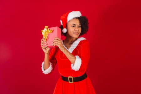 Photo for Beautiful black brazilian woman, dressed as santa claus, mama claus, finding out what is red gift - Royalty Free Image