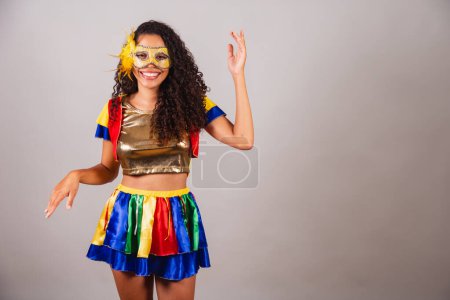 Foto de Hermosa mujer brasileña negra, con ropa frevo, carnaval. Usar una máscara, bailar samba. - Imagen libre de derechos