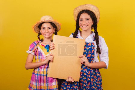 Foto de Hermanas y amigos, vistiendo ropa típica de la Festa Junina. Cartel de tenencia de texto o publicidad. - Imagen libre de derechos