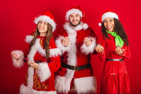 Foto de Amigos brasileños con ropa de Navidad, Santa Claus. invitando a las manos. - Imagen libre de derechos