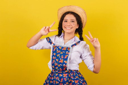 Photo for Girl wearing typical clothes for Festa Junina. making peace and love sign with fingers. For the Arraia party - Royalty Free Image