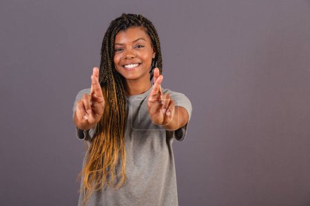 Photo for Young afro brazilian woman, hands in front, fingers crossed, wishing for luck, wishing for hope. - Royalty Free Image