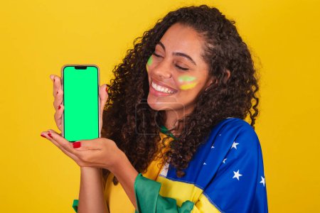 Téléchargez les photos : Jeune Brésilien noir, fan de foot. montrant l'écran de téléphone portable, smartphone. App, mobile. gros plan photo. - en image libre de droit