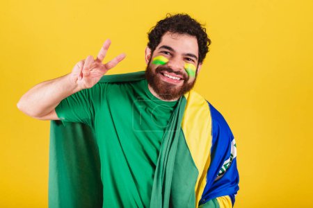 Foto de Hombre, brasileño, barbudo, fanático del fútbol brasileño, posando para selfie. Tomar fotos, posar para la foto. paz y amor. - Imagen libre de derechos
