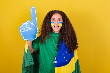 Photo for Brazilian, Caucasian, football fan girl with foam hand, screaming goal, cheering and partying. - Royalty Free Image