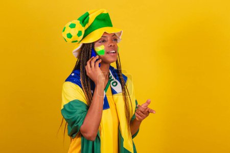 Photo for Black woman young brazilian soccer fan. using smartphone for voice call. talking. - Royalty Free Image