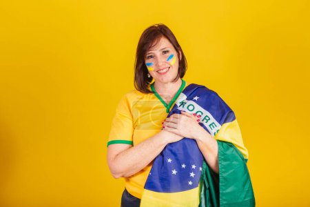 Photo for Red-haired woman, Brazilian soccer fan. with his hands on his chest singing the national anthem. Democracy. - Royalty Free Image