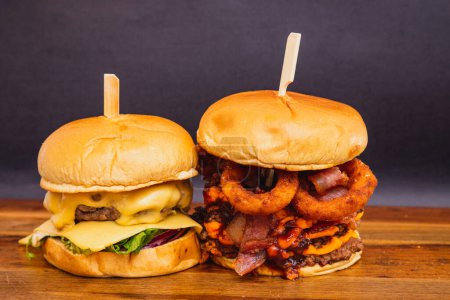 Téléchargez les photos : Deux burgers artisanaux, à base de bœuf, fromage et bacon. Rondelles d'oignon frites. - en image libre de droit