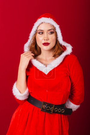 Photo for Beautiful Brazilian red-haired woman, dressed in Christmas clothes, Santa Claus. wearing hat. - Royalty Free Image