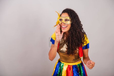 Foto de Hermosa mujer brasileña negra, con ropa frevo, carnaval. Usando una máscara, gritando promoción. - Imagen libre de derechos