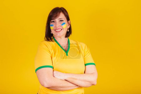 Foto de Mujer pelirroja, fan del fútbol brasileño. brazos cruzados, sonrientes, optimistas. - Imagen libre de derechos