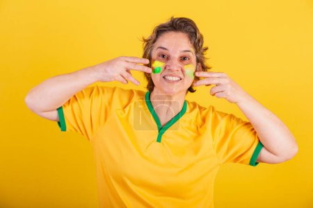 Photo for Adult adult woman, soccer fan from brazil, putting paint on her face, brazilian fans. painted face. - Royalty Free Image