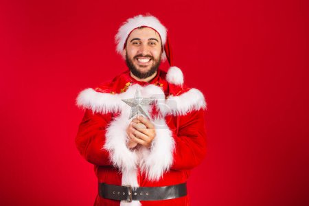 Téléchargez les photos : Homme brésilien, habillé en santa claus vêtements, tenant étoile de Noël. - en image libre de droit