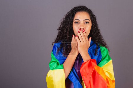 Téléchargez les photos : Jeune femme brésilienne noire, couvrant sa bouche, militant avec le drapeau LGBT, diversité, lutte contre les préjugés. - en image libre de droit