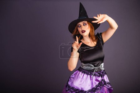 Téléchargez les photos : Répétition d'Halloween, femme caucasienne en costume de sorcière. jeter de la magie sur la caméra. - en image libre de droit