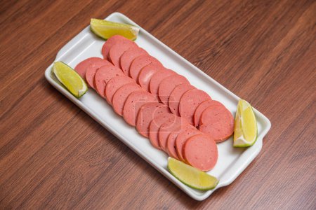 Photo for Cambu sausage, typical Brazilian snack, served with lemon slices, chili sauce and mayonnaise on wooden table - Royalty Free Image