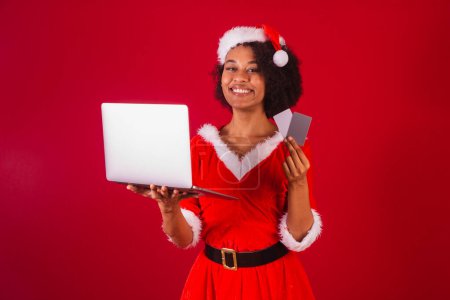 Photo for Beautiful black brazilian woman, dressed as santa claus, mama claus, holding credit cards and notebook - Royalty Free Image
