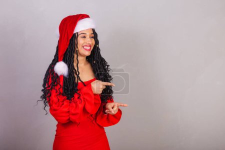 Foto de Mujer negra brasileña, vistiendo ropa de navidad, feliz navidad, sonriendo, presentando algo con sus manos. - Imagen libre de derechos