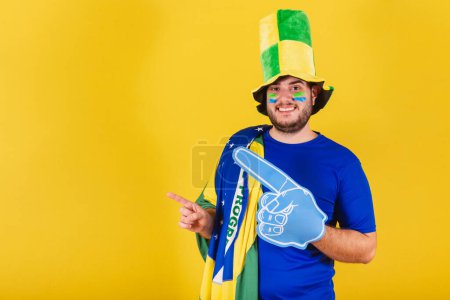 Téléchargez les photos : Homme caucasien brésilien, fan de football brésilien, chapeau, en utilisant la mousse doigt à gauche. - en image libre de droit