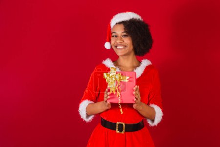 Photo for Beautiful black brazilian woman, dressed as santa claus, mama claus, holding present very happy - Royalty Free Image