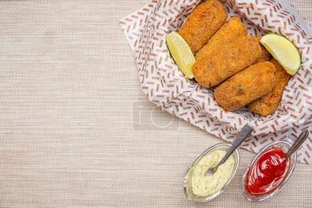 Photo for Chicken croquette, served with lemon slices, chili sauce and mayonnaise. With white towel. Seen from above. - Royalty Free Image