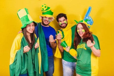 Téléchargez les photos : Groupe d'amis, les fans de football du Brésil, en utilisant le drapeau brésilien, appeler avec les mains, venez. Soyez les bienvenus. invitant. - en image libre de droit