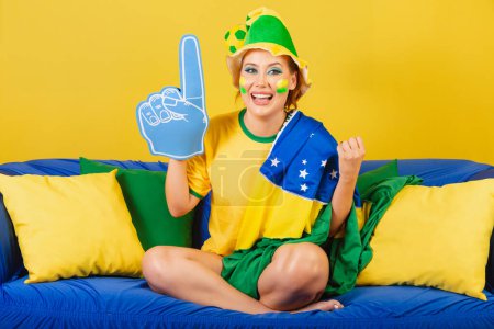 Foto de Caucásico, pelirrojo, brasileño, aficionado al fútbol brasileño en sofá con espuma dedo fiesta - Imagen libre de derechos