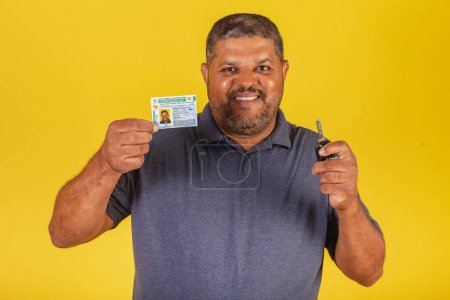 Téléchargez les photos : Homme noir brésilien, adulte avec permis de conduire, document brésilien et clé de voiture. - en image libre de droit