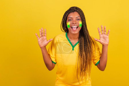 Foto de Mujer negra joven aficionada al fútbol brasileño. sorprendida, wow, increíble. - Imagen libre de derechos
