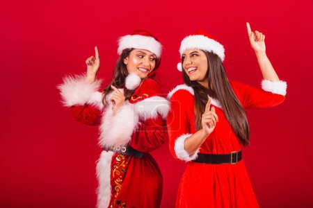 Foto de Amigas brasileñas, vestidas con ropa de Navidad, Santa Claus. bailando. - Imagen libre de derechos