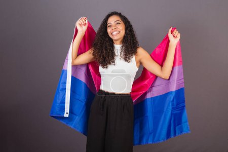 Photo for Young Brazilian black woman raising bisexual flag, Bisexual woman, LGBT, LGBTQ - Royalty Free Image