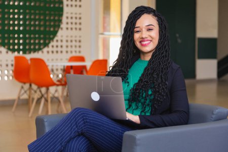 Téléchargez les photos : Jeune femme noire, brésilien, entrepreneur, femme d'affaires, dans le fauteuil, avec ordinateur portable - en image libre de droit