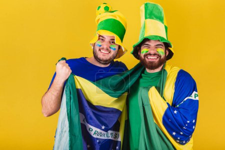 Foto de Dos amigos, brasileños, aficionados al fútbol de Brasil, animando, celebrando y vibrando en un partido de fútbol. - Imagen libre de derechos