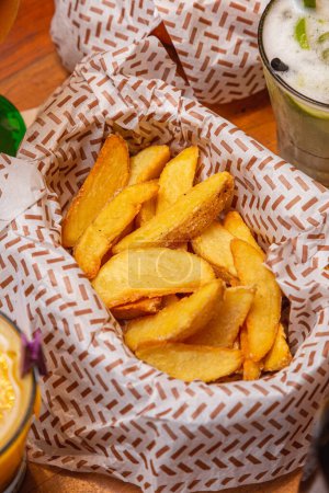 Foto de Patatas asadas rústicas, papas fritas, comida típica brasileña, servidas con caipirinha de lima. - Imagen libre de derechos