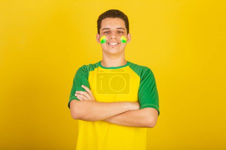 Téléchargez les photos : Jeune Brésilien fan de foot. habillé en vert, et jaune, bras croisés. - en image libre de droit