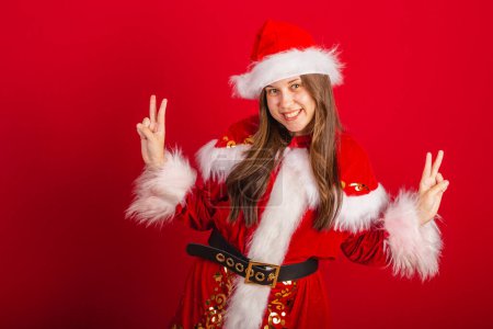 Photo for Caucasian, Brazilian woman in Christmas clothes, Santa Claus. peace and love position, selfie pose. - Royalty Free Image